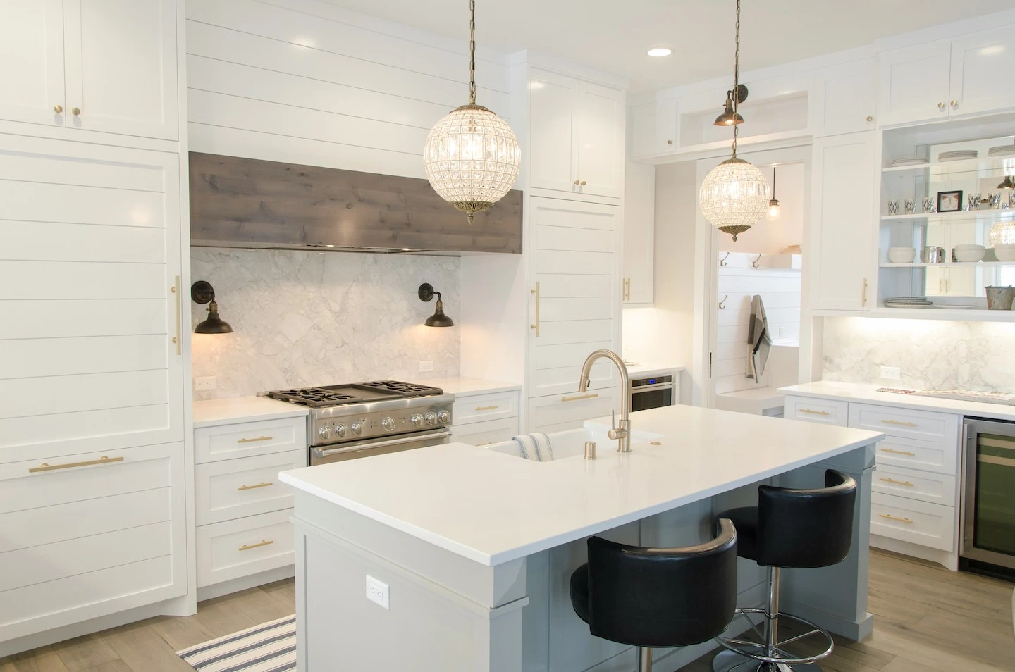 White kitchen with golden fixtures and pendant lighting.
