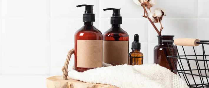 Soap dispensers on a wooden tray with a white towel draped over the tray.