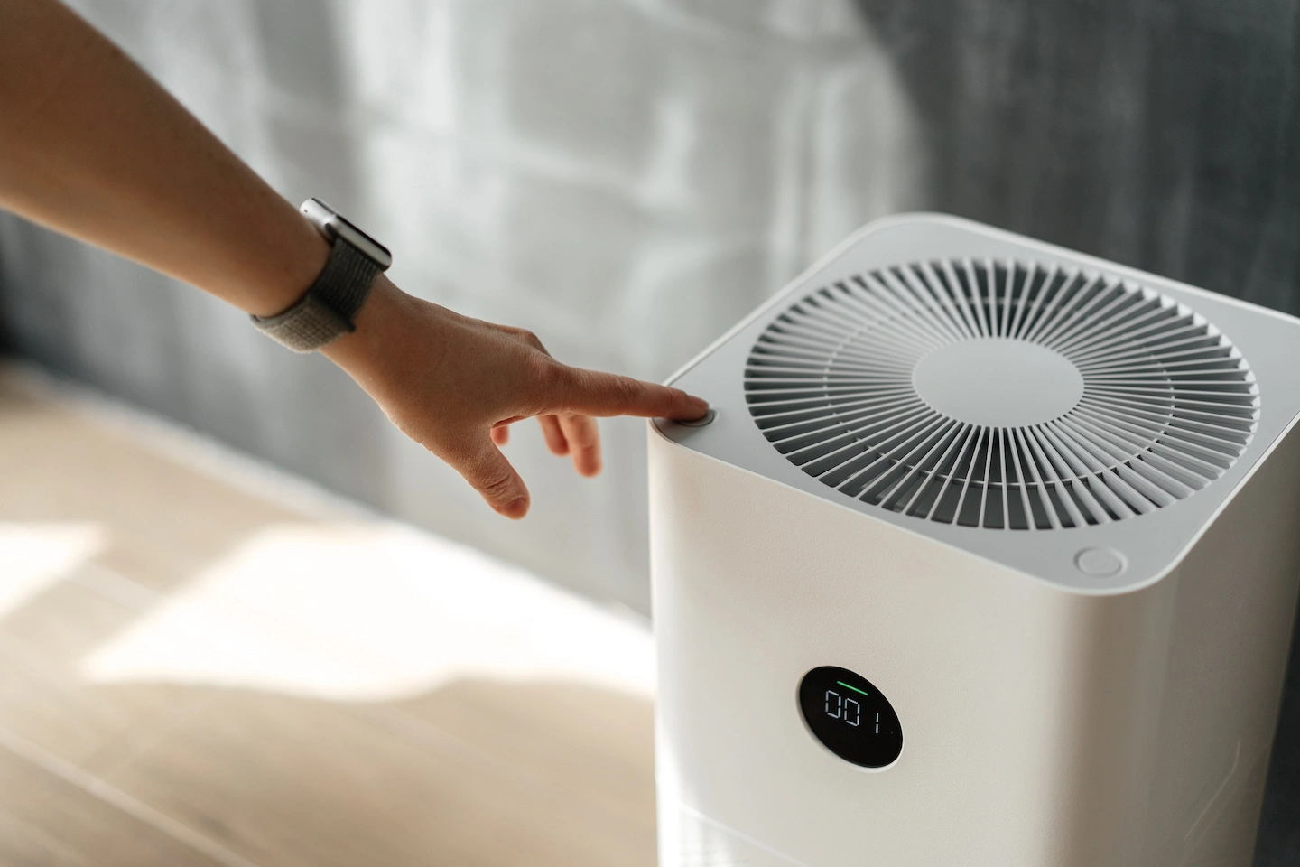 Woman pressing button to turn on air purifier in Airbnb to reduce dust.