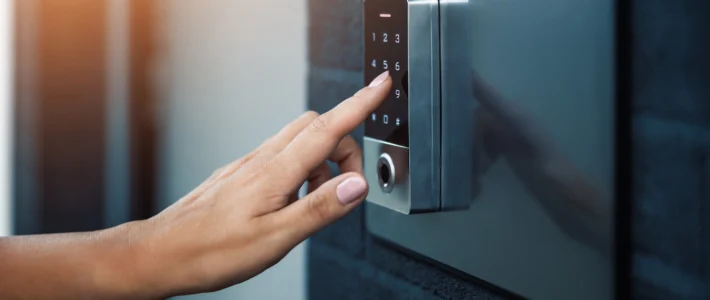 Person typing on electronic lock keypad to enter home.